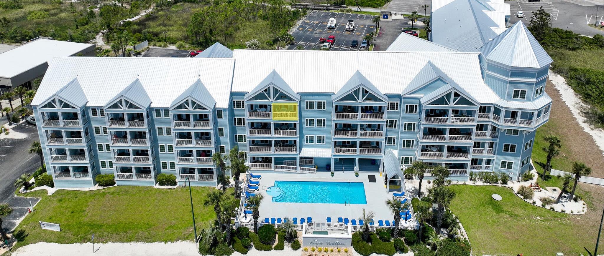Un gran resort con varias construcciones, una zona de piscina central y ubicación frente a la playa.