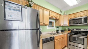 A kitchen with stainless steel appliances, wooden cabinets, and a green wall. - 🐬Gulf Front-Pool-Seaside Beach & Racquet Club-4311🐬 (Orange Beach)