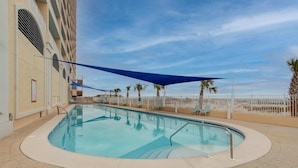 A swimming pool with a curved edge, surrounded by a brick walkway.