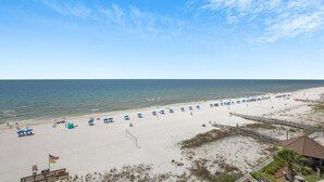 A beach with umbrellas and beach chairs, a sandy shore, and a clear sky.