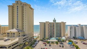 A hotel with multiple floors, a parking lot, and a view of the beach.