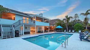 A two-story house with a swimming pool, outdoor seating, and a covered patio area.