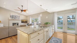 A modern kitchen with a central island, a ceiling fan, and a large window.
