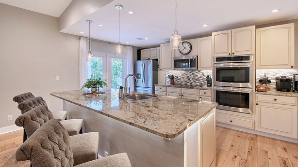 A modern kitchen with a large island, stainless steel appliances, and pendant lighting.