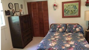 Ein Schlafzimmer mit einem Bett, einem Schminktisch, einem Kleiderschrank und einer Wanduhr.