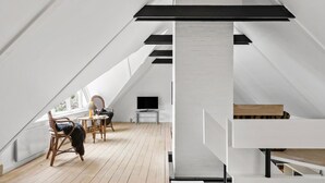 A modern loft bedroom with a sloped ceiling, wooden flooring, a central black beam, and a seating area with a table and chairs. - Stunning home in Hurup Thy with WiFi (Hurup Thy)