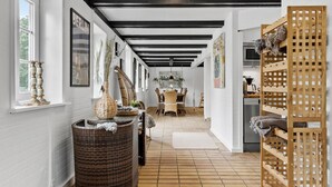 A hallway with a dining area, wicker furniture, and a wooden rack with towels. - Stunning home in Hurup Thy with WiFi (Hurup Thy)