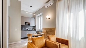 Una sala de estar moderna con un sofá, una mesa de comedor y una cocina al fondo.