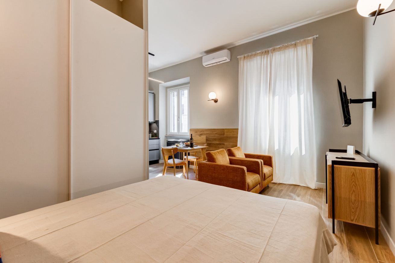 A bedroom with a bed, a desk, a chair, and a TV.
