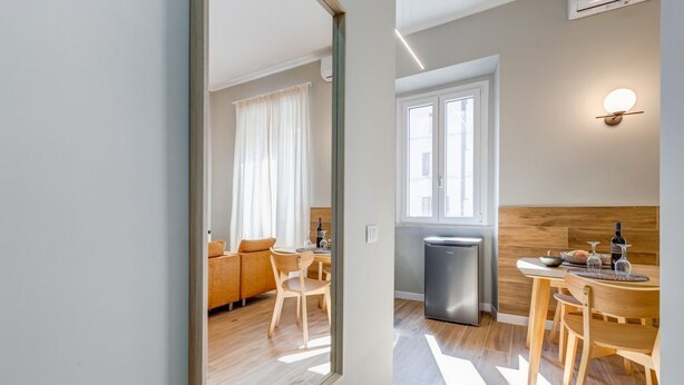 Una cocina moderna con refrigerador, un comedor con mesa y sillas, y una sala de estar con sofá y mesa auxiliar.