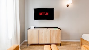 Una habitación moderna con un mueble de madera, un televisor montado en la pared y una mesita de noche.