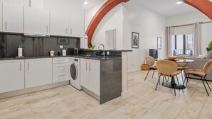 A modern kitchen with white cabinets, a black countertop, and a built-in washing machine. - In downtown Funchal, Tanoeiros Residence II (Funchal)