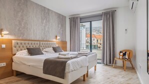 Une chambre d’hôtel moderne avec un grand lit, une vue sur la ville et un balcon équipé d’une chaise.
