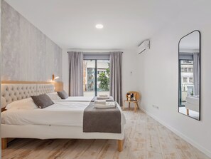A modern bedroom with a large bed, a chair, and a view of the city.