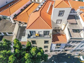 A multi-story building with red-tiled roofs, balconies, and air conditioning units.