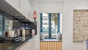 Une cuisine moderne avec un plan de travail noir, des armoires blanches et un coin fenêtre agrémenté de coussins.