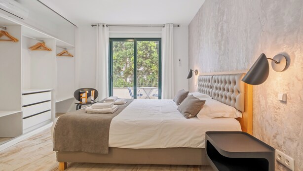 Une chambre moderne avec un grand lit, une armoire, un coin salon et une vue par la fenêtre.