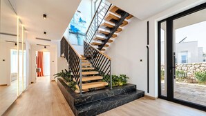 Een moderne trap met houten treden en zwarte leuningen, die uitkomt op een balkon met uitzicht over de stad.