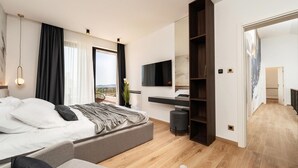 Een moderne slaapkamer met een bed, een televisie, een kledingkast en uitzicht op een balkon.