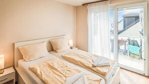 A double bed with two pillows and a nightstand with a lamp.