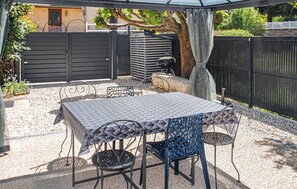 A covered patio with a table and chairs, a grill, and a black fence. - Stunning apartment in Trouvans with WiFi (Trouvans)