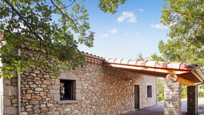Ein Steinhaus mit rustikaler Steinwand und einer Holzpergola.