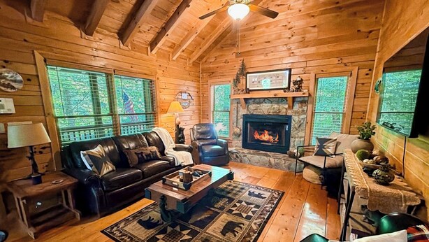 Un interior de cabaña acogedor con chimenea, muebles de cuero y suelo de madera.