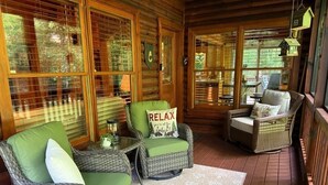 Interior acogedor de una cabaña de madera con muebles de mimbre, una alfombra y una almohada con la palabra 'RELAX'.