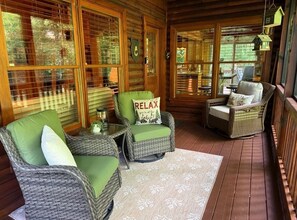 A cozy wooden cabin interior with wicker furniture, a rug, and a 'RELAX' pillow. - Cabin with a Creek   Screened porch.  Pet Friendly (Blue Ridge)