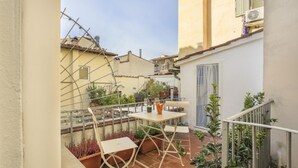 A small outdoor patio with a table and chairs, surrounded by potted plants and a metal railing. - Cinque Passi - Sweet Dreams in Florence (Firenze)