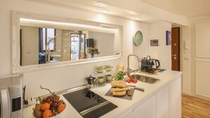 A modern kitchen with a large mirror, a sink, a coffee maker, and a fruit bowl. - Cinque Passi - Sweet Dreams in Florence (Firenze)