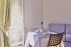 Un comedor con una mesa dispuesta para dos personas, una botella de vino y copas.