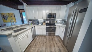 A modern kitchen with white cabinets, stainless steel appliances, and a wooden floor. - Tennis Townhomes 1323 (Keystone)