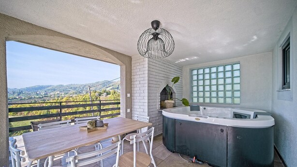 A patio area with a wooden table and chairs, a hot tub, and a view of the countryside. - Nice home in Ivancici with house a mountain view (Ivancici)