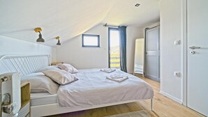 A bedroom with a bed, a wardrobe, a window with curtains, and a door. - Nice home in Ivancici with house a mountain view (Ivancici)