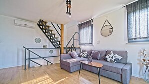 A modern living room with a grey sectional sofa, a small wooden coffee table, and a staircase with black railings. - Nice home in Ivancici with house a mountain view (Ivancici)