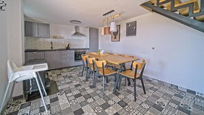 A compact kitchen with a dining area, featuring a patterned floor, a wooden dining table, and a staircase with a geometric design. - Nice home in Ivancici with house a mountain view (Ivancici)