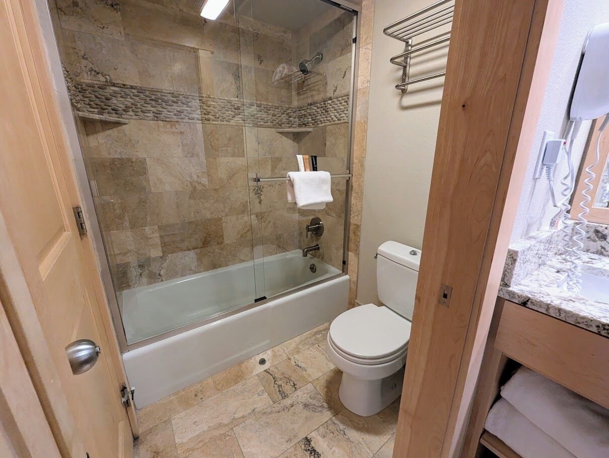 Un baño con ducha de vidrio, inodoro blanco y encimera de mármol.
