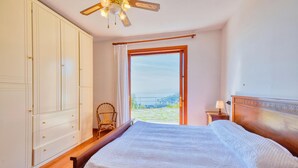 A bedroom with a bed, a wardrobe, a chair, a nightstand, and a view of the outdoors. - Amazing home in Recco with WiFi (Recco)
