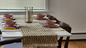 Une table à manger dressée avec des bols et des assiettes roses, un set de table en fibres tressées et un porte-bougie décoratif.