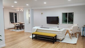 Un salon moderne comprenant un canapé, un banc, un téléviseur et un coin repas.
