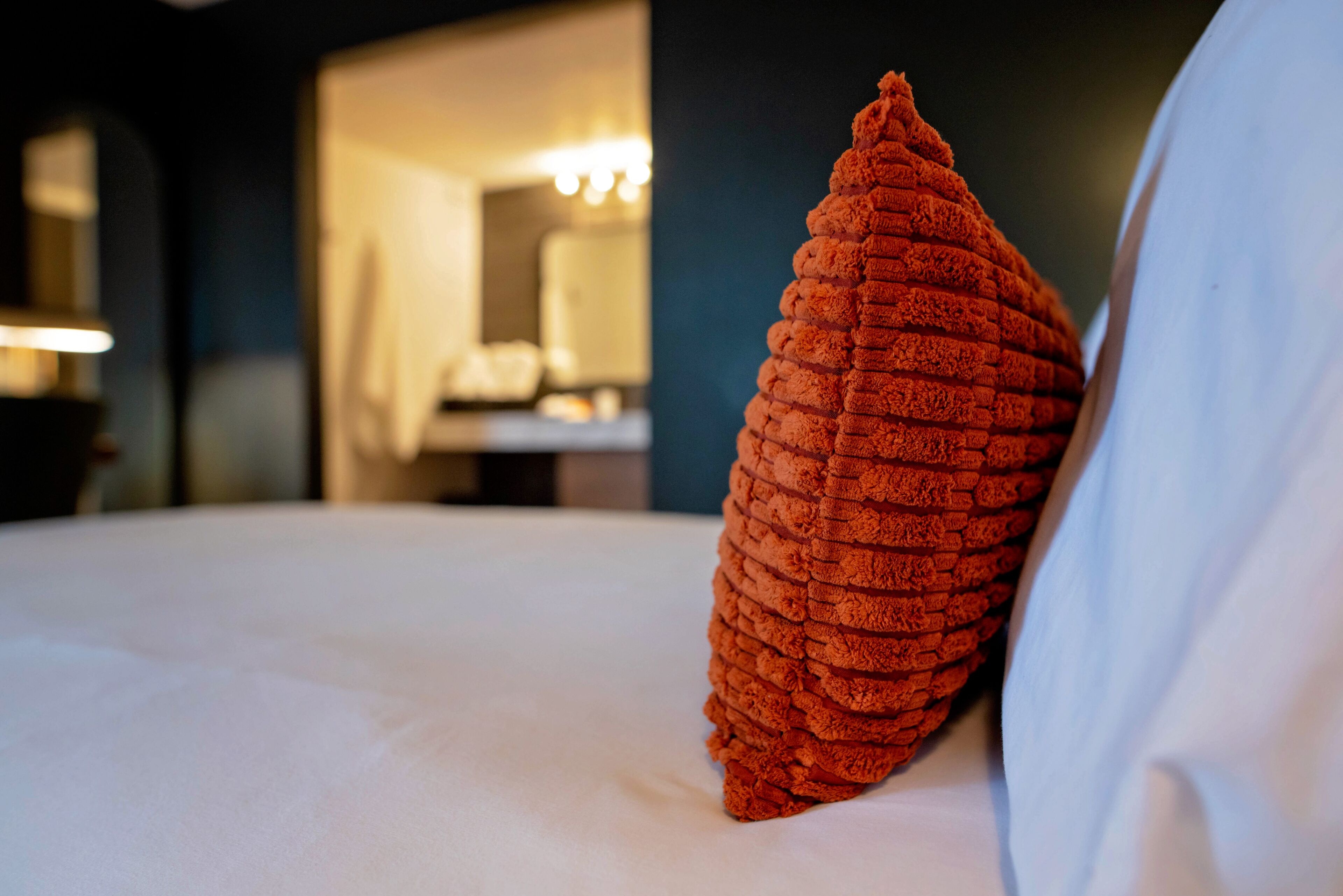 Un lit avec un oreiller à texture et un drap blanc.