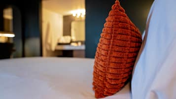 A bed with a textured pillow and a white sheet.