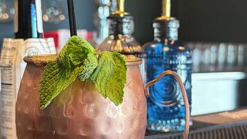 A copper mug with a handle and a green leaf garnish, placed on a textured surface.