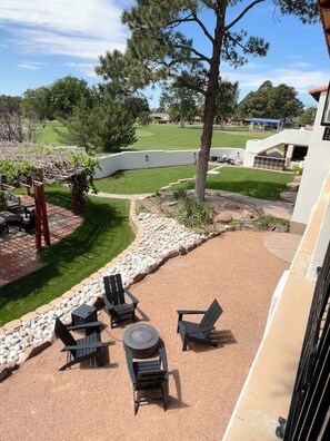 A patio with outdoor furniture, a pergola, and a view of a well-maintained lawn and trees. - El Verde Inn (Albuquerque)