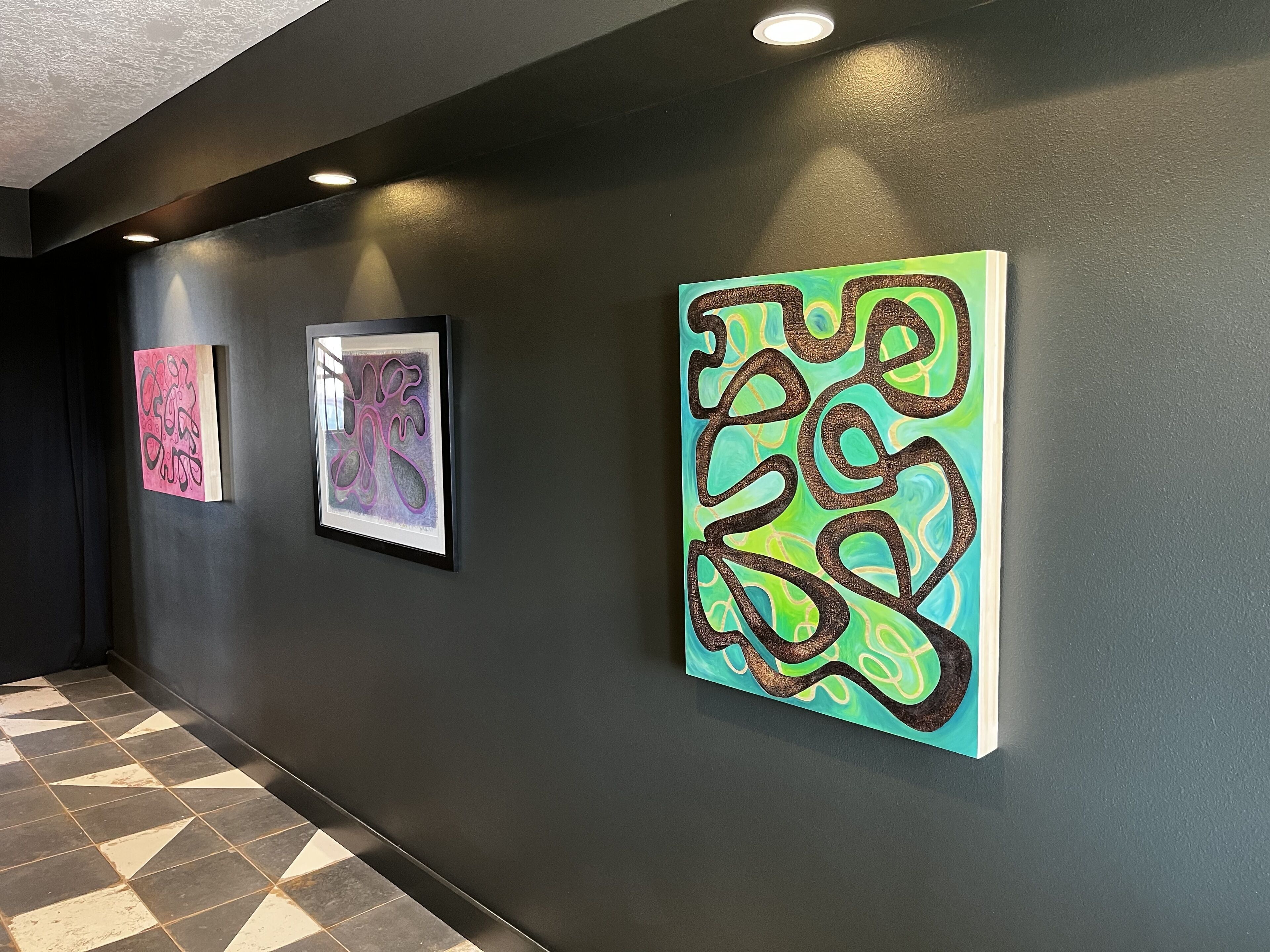 A hallway with three framed artworks on the wall.