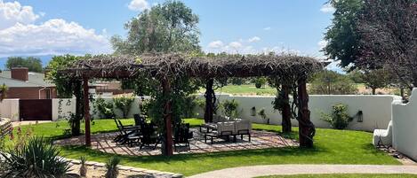 Un jardín bien cuidado con una pérgola, asientos al aire libre y un sendero despejado.
