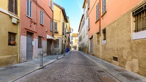 Una calle empedrada bordeada por edificios con contraventanas y un cielo despejado.