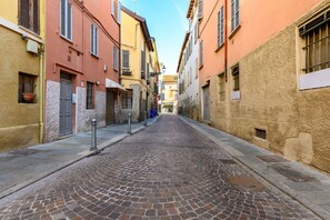 A cobblestone street flanked by buildings with shutters and a clear sky.