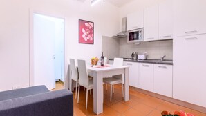 Una cocina moderna con armarios blancos, microondas y un comedor con mesa y sillas.